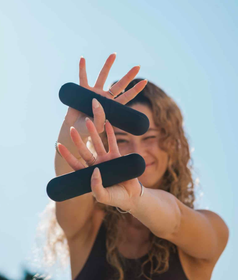 אישה מחייכת מחזיקה בשני מזרני רפורמר שחורים