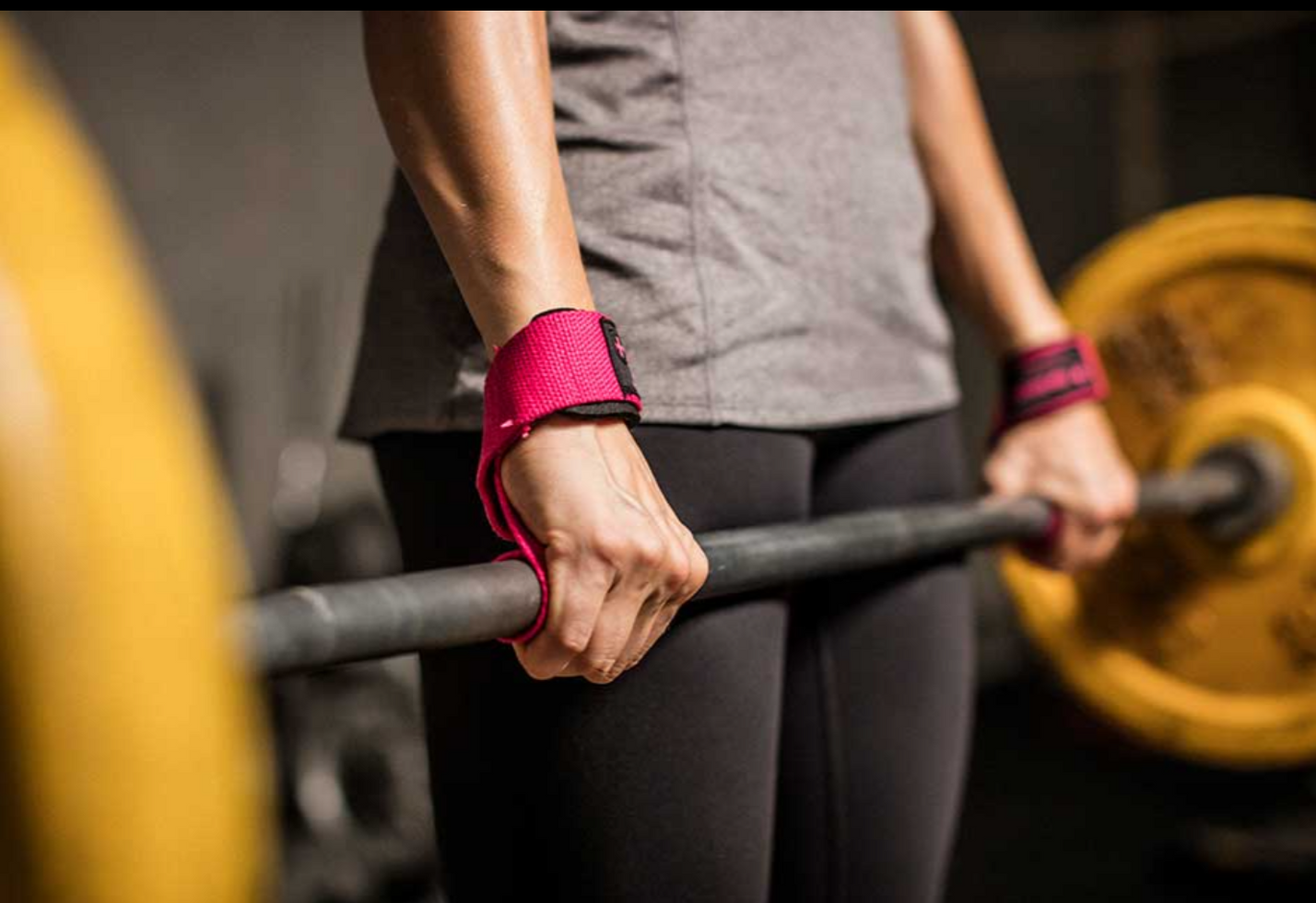 אישה אוחזת במוט משקולות עם רצועות אחיזה ורודות