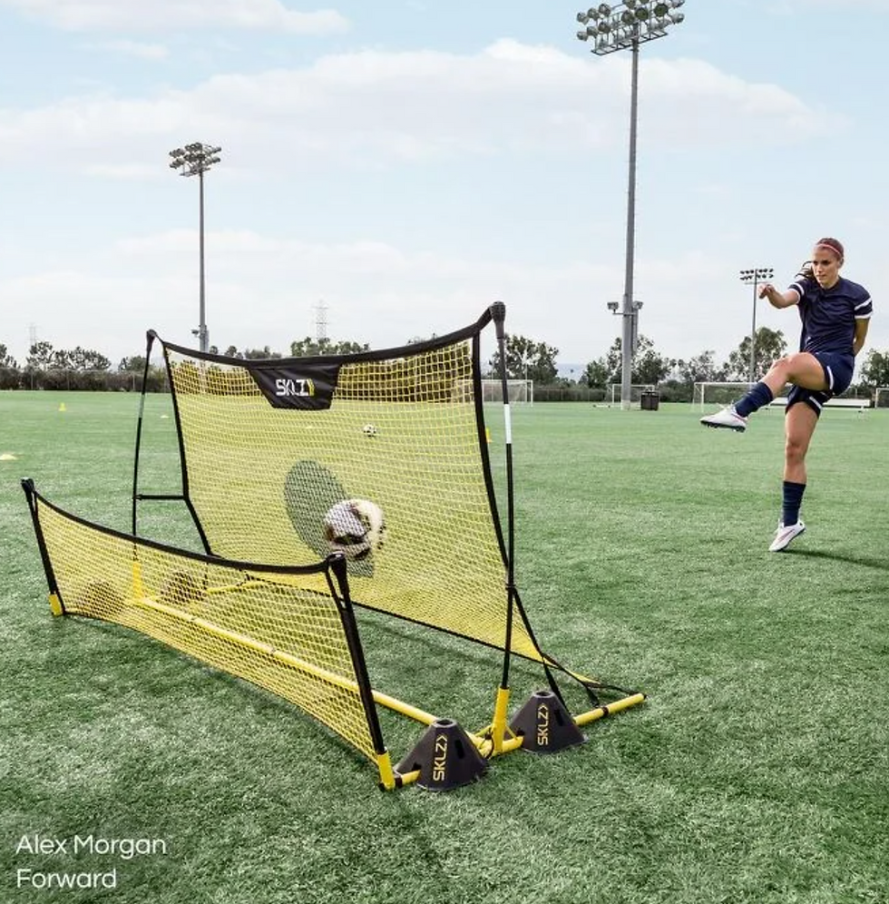 כדורגלנית בועטת בכדור לעבר רשת אימון