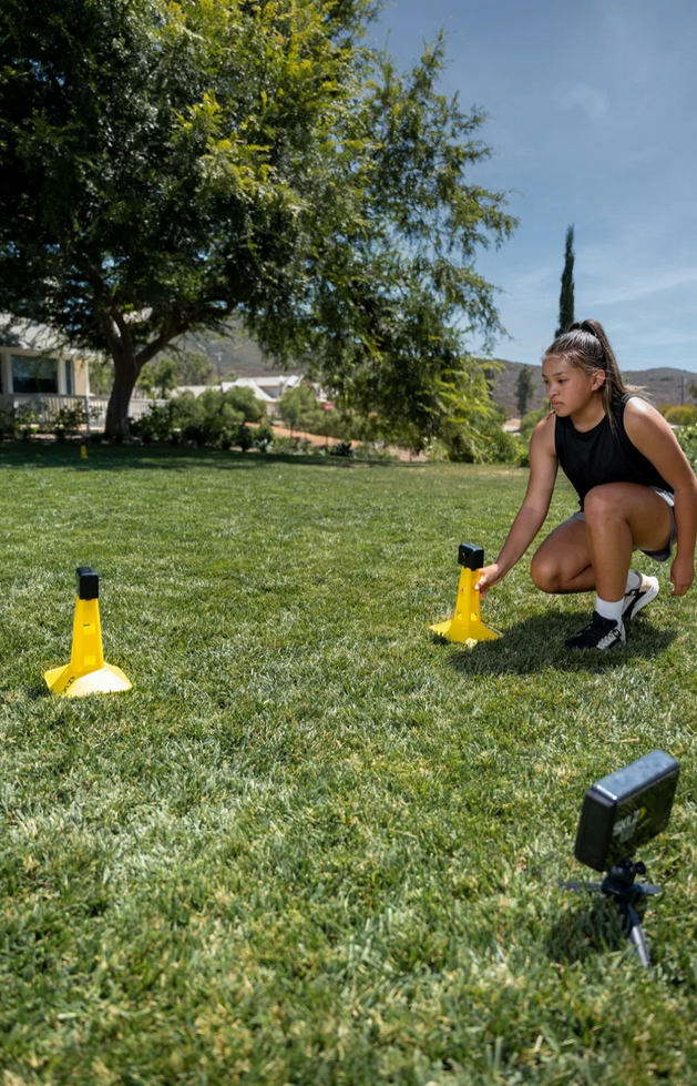 נערה מסדרת קונוסים צהובים על הדשא
