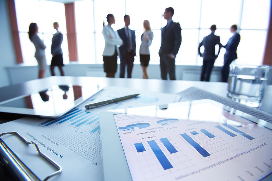 Close-up of business document in touchpad lying on the desk, office workers interacting in