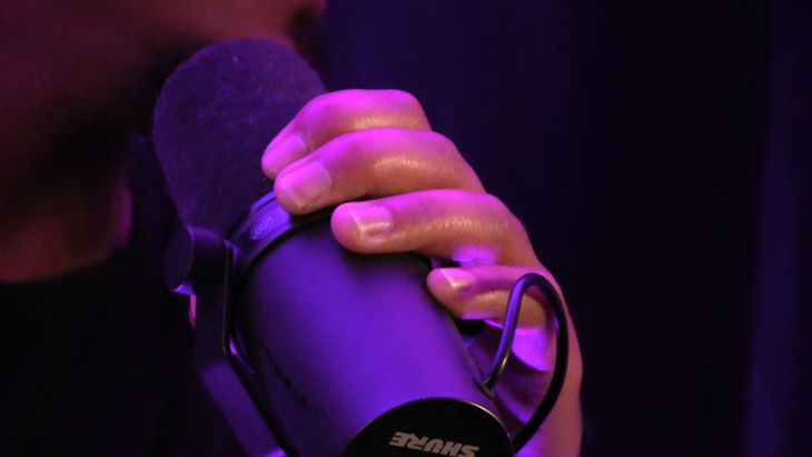 Close-up of a hand resting on a purple-lit shoulder or upper arm.
