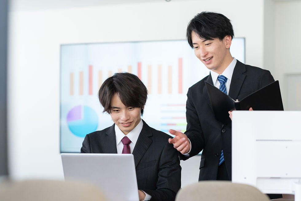 ノートパソコンで資料を確認しながら打ち合わせをする二人のビジネスマン