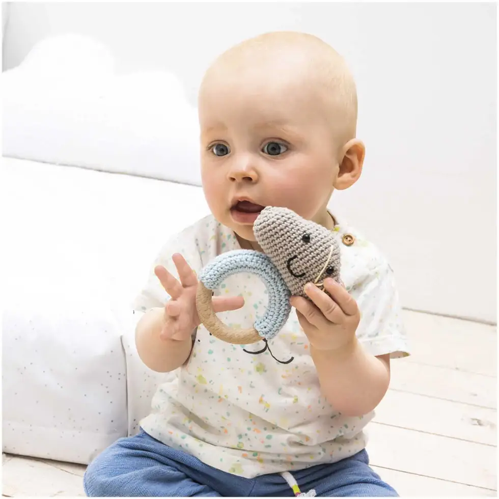 004 Rico Creative Ricorumi DK, gris perle 25 g, 57.5 m, bébé tenant en main un hochet amigurumi fait avec Ricorumi DK