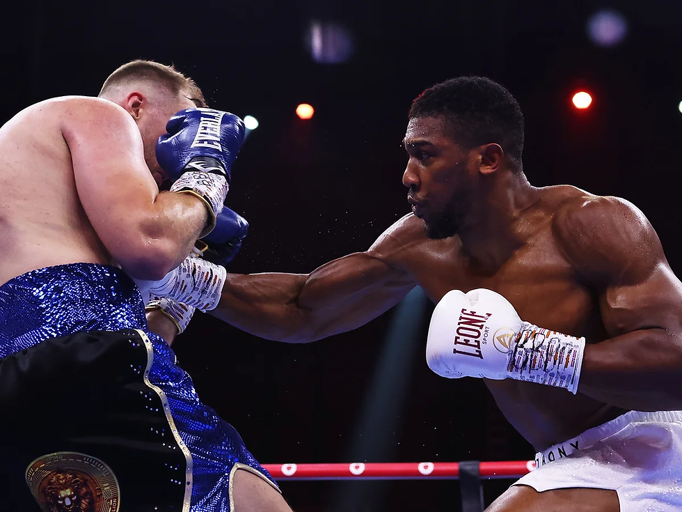 Boxer in white gloves punches opponent in blue sequin shorts. Intense action in boxing ring, spotlights in background.