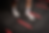 Feet in white sneakers on a red agility ladder on a black textured floor. The setting suggests a fitness or training environment.