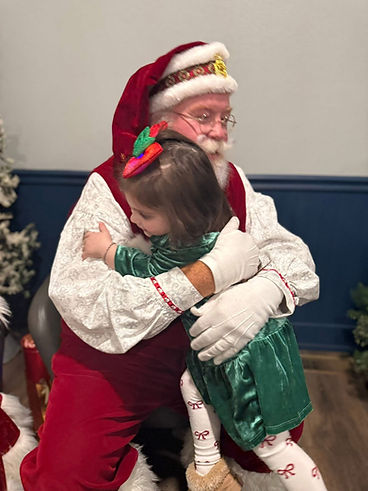 Little girl giving Santa Bryan a big hug
