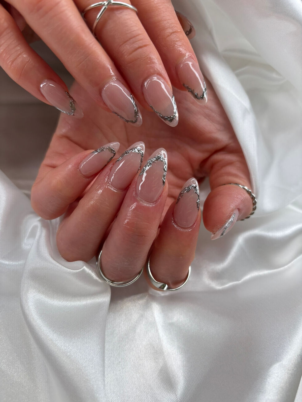 Nude nails with metallic silver outline chrome detail, glossy almond finish at Robson Nails & Spa, downtown Vancouver