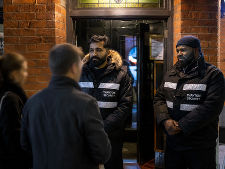 Two professional Thantom Security guards outside a London venue entrance, calmly speaking with customers while providing event security cover.