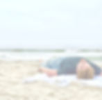Man laying on the sand with the beach crashing ahead