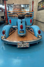 Rear view of a blue custom pit bike on a custom VW trailer behind a Reborn VW Bus.