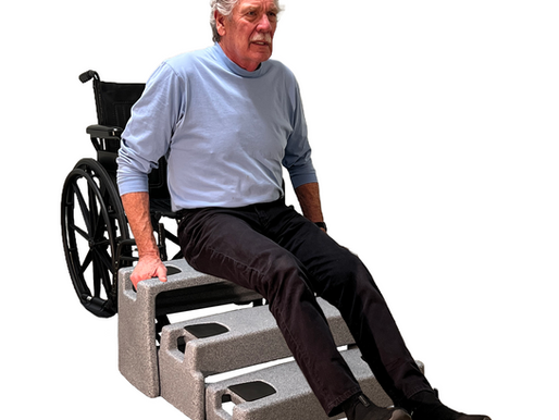 Man in blue shirt uses gray fall recovery device to get up to his wheelchair. White background.