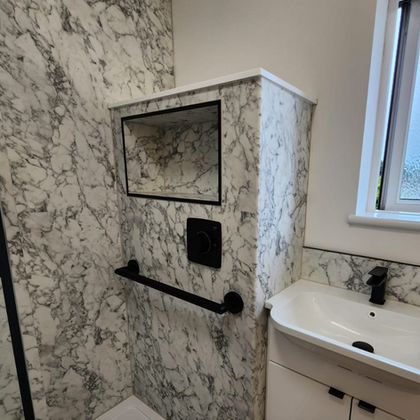 Marble-patterned bathroom wall with black fixtures and sink