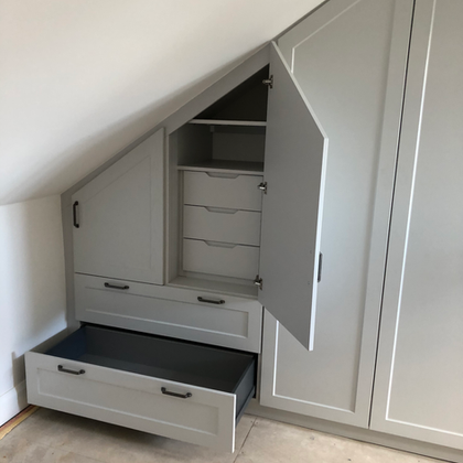 Fitted wardrobe under sloped ceiling with open drawers