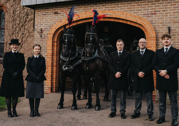 The staff at John Brown and Daughter Funeral Services stood with two black horses 