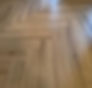 Close up of wooden flooring, can see the panels intersecting, shiny floor