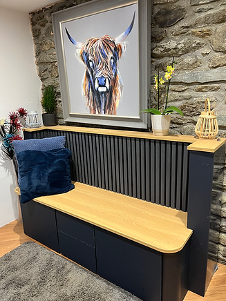 Navy blue storage bench with wooden seat against a stone wall, painting above