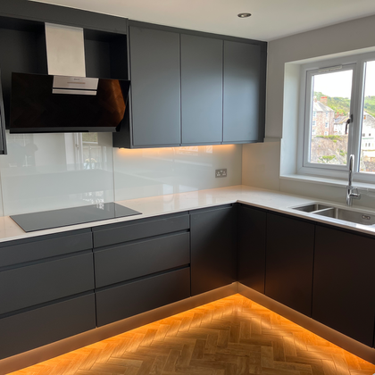 Dark grey fitted kitchen with light counters and accent lighting