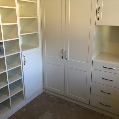 Built-in cream closet with open shelves, double doors, and drawers