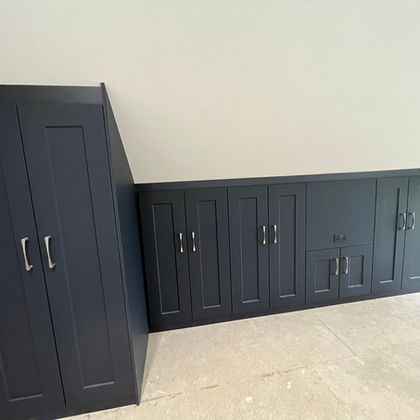 Dark blue fitted wardrobes in a sloped ceiling room
