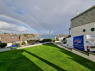 Double rainbow over a seaside town with a green lawn