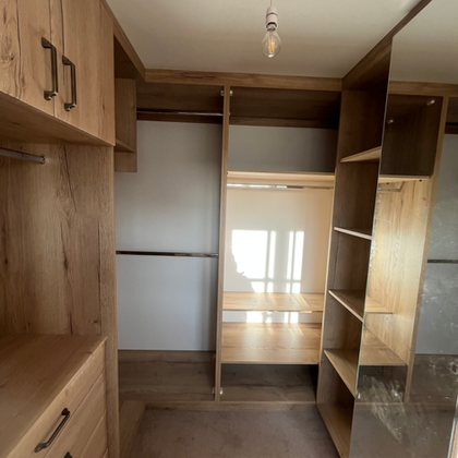 Empty bespoke wooden closet with shelves and hanging rods