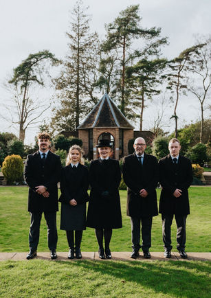 The staff at John Brown and Daughter Funeral Services stood in a patch of green grass with a gazebo behind them
