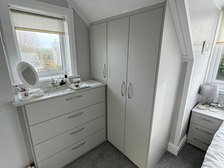 Light grey fitted wardrobe and dresser in bedroom corner