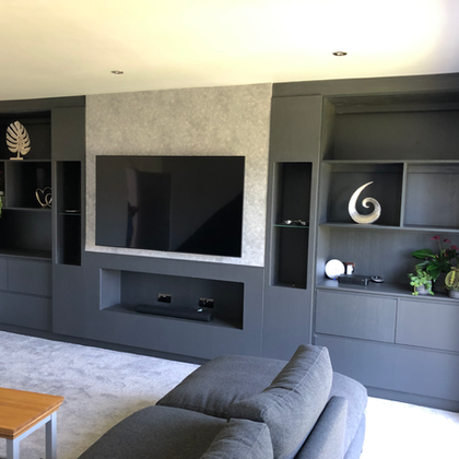 Modern media wall with large TV, dark gray cabinets, and shelving.