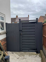 New black garden gate installed by the side of a home