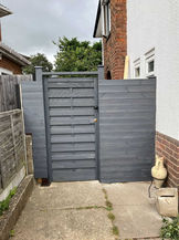 New black garden gate installed by the side of a home