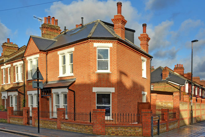 Outside of a home, brick walls, white windowsills, black tslate roof