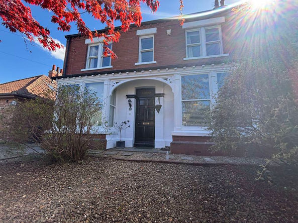 Exterior of a home taken from the front garden, brick coloured with white highlights over the home