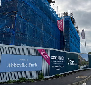 Construction site wrapped in blue netting with scaffolding, featuring signs for "Places for People" and "SGE Services"