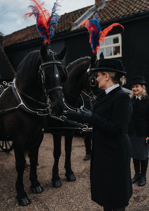 Funeral Operatives stood by horses at a funeral service 