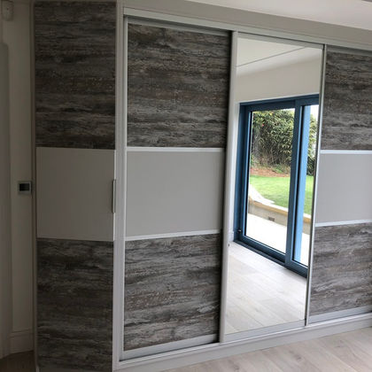 Fitted wardrobe with sliding gray and mirrored doors