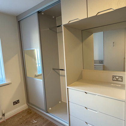 Fitted wardrobe with sliding mirrored doors and chest of drawers