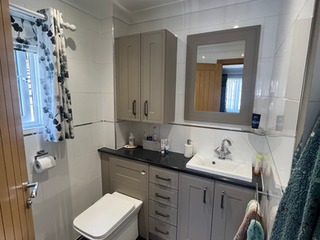 Modern bathroom with gray vanity, white toilet, and patterned curtain