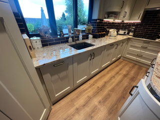 Kitchen with light cabinets, speckled countertop, and sink