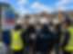 Three construction workers in hard hats and SGE-Services branded clothing examine blueprints