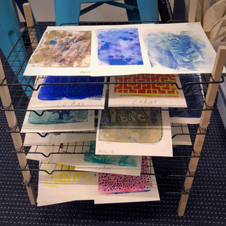 A home made drying rack made with cookie racks, with kids' prints drying