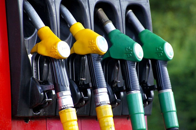 Close-up of four fuel pump nozzles, two yellow and two green, lined up on a gas station dispenser.