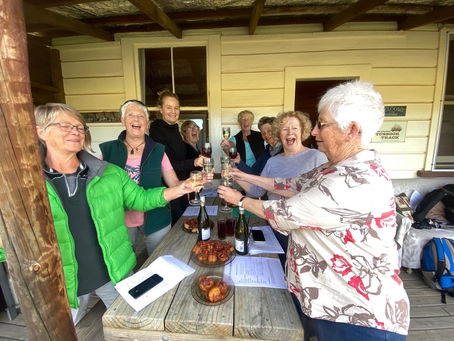 Eight women raising a toast together on a hut veranda during a Sidetracks Women tour.