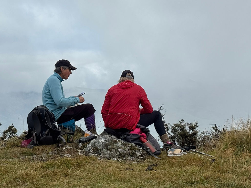Two women enjoying a relaxed break during a guided hiking tour in New Zealand, sharing conversation and the companionship that makes small-group travel special.