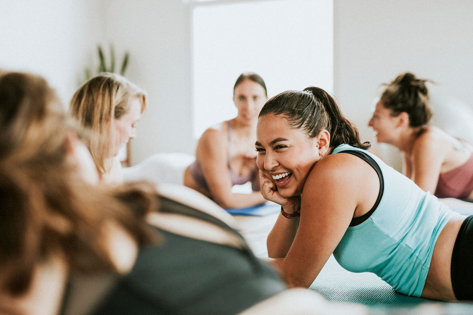 Group of happy women lying down in a circle wearing active wear