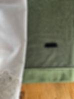 White lace fabric adjacent to green textured material with a black Velcro strip on a wooden surface. Warm and rustic setting.