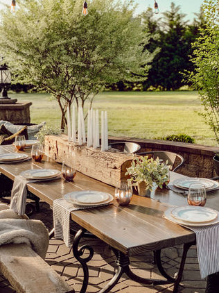 An outdoor patio with spring green trees around a DIY table with romantic rustic candle holder
