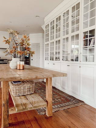 A european farmhouse kitchen with glass front cabinet and rustic handmade baking table
