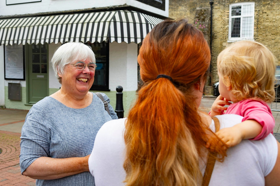 Charlotte Cane talking to a woman who is holding a child.