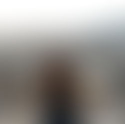 A woman in a harness stands smiling on a high ledge outside of Taipei 101's 91st floor with a vast cityscape below, mountains in the distance, and a cloudy sky above.